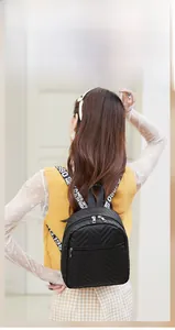 Close-up of black V-quilted backpack with stylish wide-lettered fabric shoulder strap