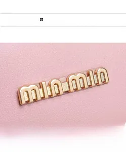 Close-up of pink litchi grain leather texture and elegant golden metal brand lettering