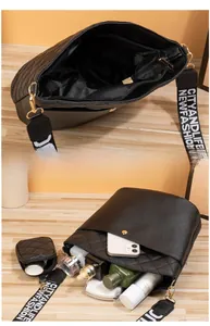 Detail view of black quilted bucket bag with wide lettered strap and small pouch