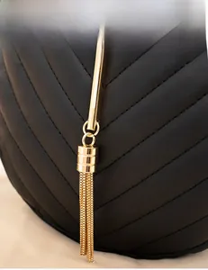 Close-up of black V-quilted leather texture and elegant gold chain tassel detail