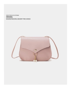 Detail of pink small square bag featuring a gold ring with pearl fringe and flap closure