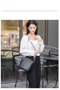Close-up of black crossbody bucket bag with quilted patterns and a wide patterned strap