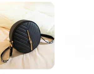 Detail of black V-quilted round shoulder bag with golden zipper and fringe tassel