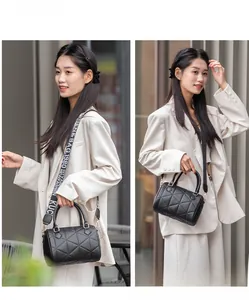 Détail du sac Boston en cuir matelassé noir avec bandoulière large à logo tendance
