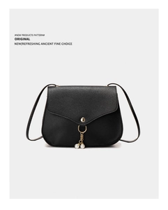Close-up of black lychee leather crossbody bag with gold buckle and pearl pendant detail