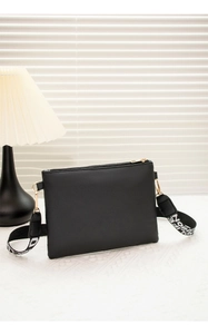 Détail du sac bandoulière noir avec sangle tissée et finitions zippées dorées