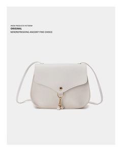 Close-up of white crossbody bag featuring a golden buckle and double pearl pendant detail