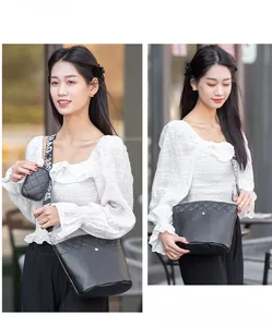 Detail of black quilted bucket bag featuring a wide embroidered strap and mini coin purse