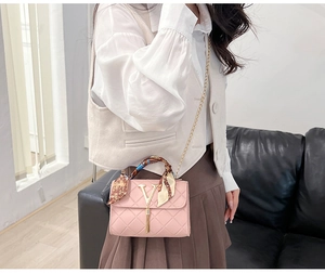 Pink quilted crossbody bag with silk scarf handle and gold chain worn by model