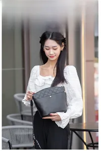 Detail of black quilted leather bucket bag with gold lock and stylish wide shoulder strap