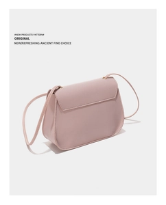 Detail of a dusty pink leather crossbody bag with gold metal hardware and flap closure