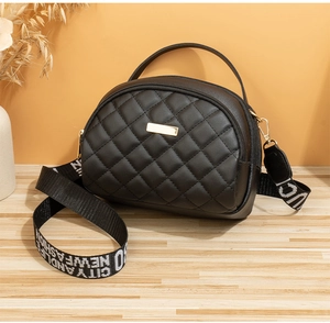 Détail du sac matelassé noir avec bandoulière contrastée et garnitures dorées