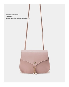 Detail of a dusty pink crossbody bag with a gold snap closure and dual pearl pendant