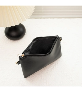 Détail du sac à bandoulière noir avec fermeture éclair dorée et rangement intérieur