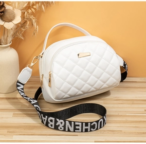 Gros plan d'un sac bandoulière blanc matelassé avec détails dorés et bandoulière