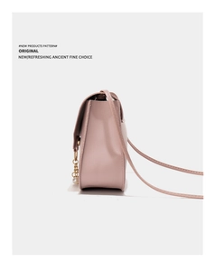 Detailed side view of pink faux leather crossbody bag with gold chain and pearl charm