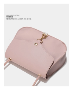 Detail of light pink shoulder bag with gold magnetic clasp and pearl tassel charm