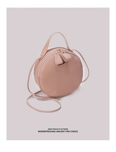 Détail du sac à bandoulière rond rose à motif litchi avec décoration métallique