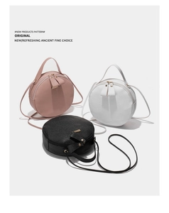 Détail de sacs bandoulière ronds en rose, blanc et noir avec texture litchi