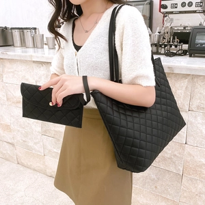 Quilted black tote bag with matching pouch on shoulder of model in lifestyle setting