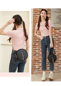 Detail of black round crossbody bag with V-quilted pattern and gold tassel accessory