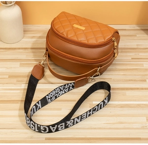 Détail d'un sac bandoulière marron semi-circulaire avec rabat matelassé et sangle
