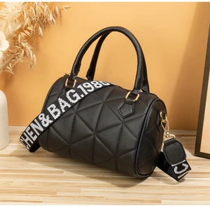 Détail du sac Boston noir matelassé avec bandoulière lettrée et boucles dorées