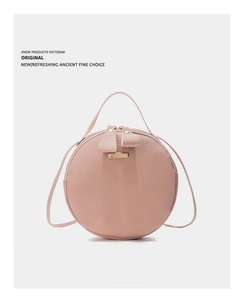 Détail du sac à bandoulière rond rose avec texture grainée et finitions métalliques