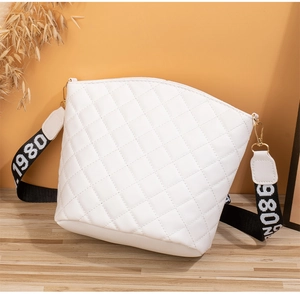 Detail of white quilted bucket bag featuring a woven strap with 1980 numbering