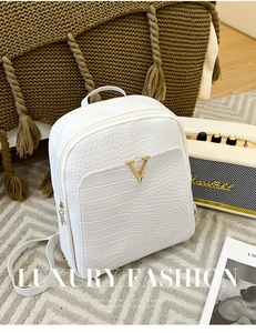 Detailed view of white crocodile pattern backpack with gold V logo and premium hardware