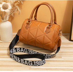 Détail du sac Boston en cuir matelassé marron avec large bandoulière tissée
