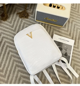Detail of white crocodile pattern backpack with golden V-shaped metal hardware accessory