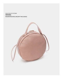 Gros plan du sac rond rose clair à texture grainée avec fermetures éclair dorées chic