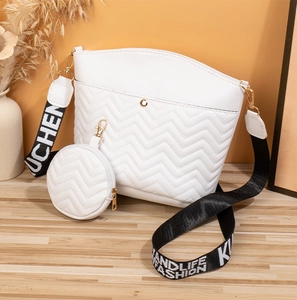 Close-up of white chevron quilted bucket bag with a round coin purse and woven strap