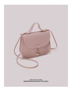 Detail of light pink saddle bag featuring gold magnetic clasp and elegant double pearl charms