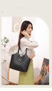 Close-up of black quilted leather tote bag with gold flower logo on a white shirt model