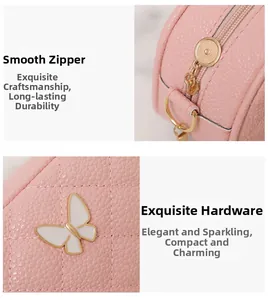 Détail du sac en cuir litchi rose avec ornement papillon et fermeture éclair dorée