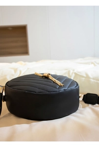 Detail of black round shoulder bag with V-quilted faux leather and gold chain tassel