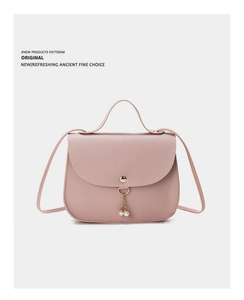 Detail of light pink crossbody bag with gold buckle and pearl charm accessory