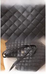 Detailed view of black quilted leather stitching and golden flower metal hardware of the tote bag
