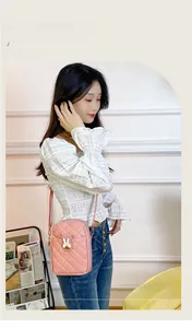 Detail of pink quilted crossbody bag featuring a cute metal rabbit-shaped buckle