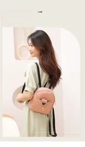 Detail of pink quilted PU leather backpack with gold heart lock on model in green dress