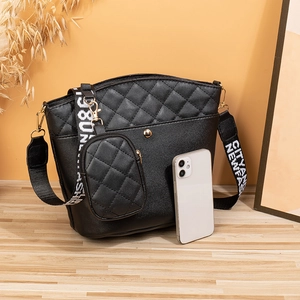 Black quilted bucket bag with circular coin purse and stylish woven strap in a warm setting