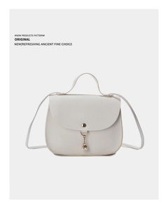 Close-up of cream white crossbody bag with lychee texture and pearl tassel detail