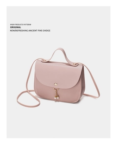 Close-up of soft pink PU leather handbag with gold buckle and pearl chain detail