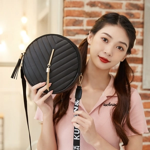 Sac bandoulière rond matelassé noir avec pompon doré et sangle jacquard sur modèle