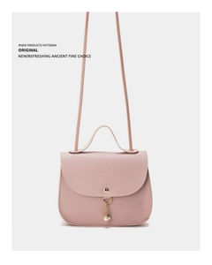 Detail of pink faux leather handbag featuring a pearl charm and golden magnetic closure