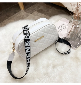 Detail of white quilted crossbody bag with golden logo and woven letter shoulder strap