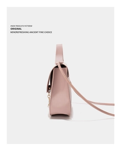 Detailed side view of pink faux leather handbag with pearl charm and gold hardware