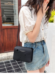 Detail of minimalist black crossbody cheese bag with hollow circular cutouts for women
